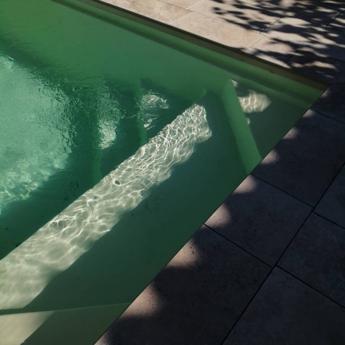 Pose d'une petite piscine en coque polyester  de 4.50M X 2.20M avec un escalier entourée d'une terrasse en carrelage imitation travertin , sur la commune de Léognan proche de Gradignan